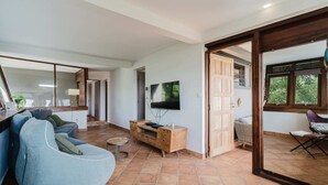 A spacious living area with a large TV, a blue sofa, and a wooden entertainment unit. - Villa Kaléna - Four Bedroom Villa, Sleeps 9 (Le Diamant)