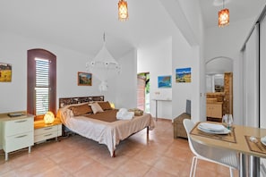 Une chambre à coucher avec un lit, une table de chevet, une lampe et une œuvre d’art.