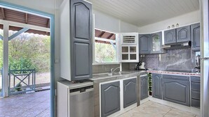 Eine Küche mit grauen Schränken, einem Edelstahl-Kühlschrank und einer gefliesten Spritzschutzwand.