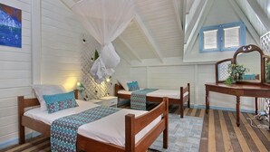 Ein gemütliches Zimmer mit zwei Holzbetten, einem Schminktisch mit Spiegel und einem Deckenventilator.