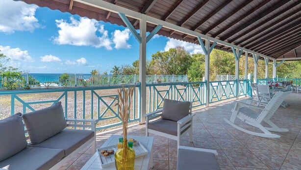 Eine Außenpatio mit Sitzgelegenheiten, Meerblick und einem überdachten Bereich mit Fliesenboden.