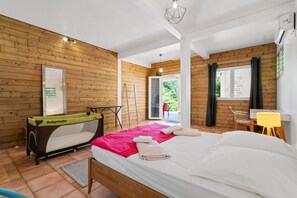 Ein Zimmer mit einem Bett, einer Holzwand, einem Fenster und einer Tür, die zu einem Außenbereich führt.