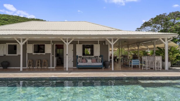 A house with a covered porch, a pool, and a garden.