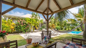 A covered outdoor seating area with a pool, surrounded by lush tropical plants and a hammock. - Villa Kaline - Three Bedroom Villa, Sleeps 6 (Le Vauclin)