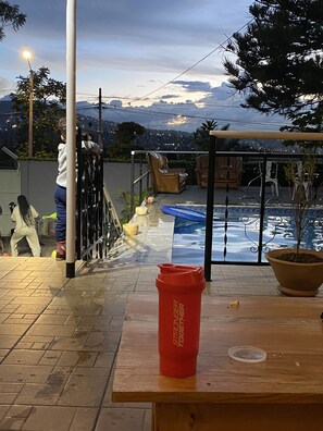 A patio area with a pool, outdoor seating, and a view of mountains. - One Room Beautifully Studio, With Breakfast (Kigali)