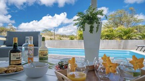Ein Tisch mit Getränken, Snacks und Blick auf ein Schwimmbad.