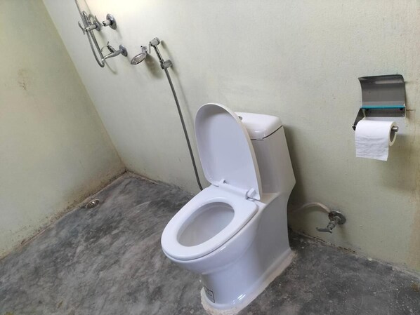 A standard bathroom with a toilet, a hand dryer, and a paper towel dispenser.
