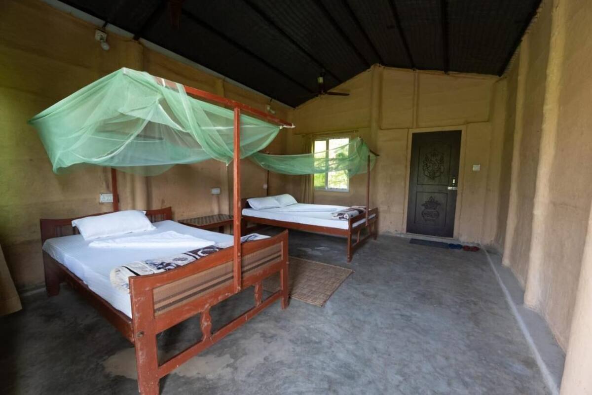 Ein Zimmer mit zwei Holzbetten, eines davon mit Moskitonetz.