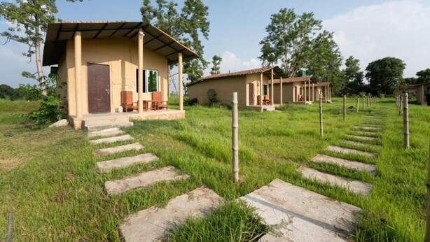 Un paysage rural avec un petit bâtiment doté d’un toit en tuiles et d’une porte, entouré d’herbe et d’arbres.