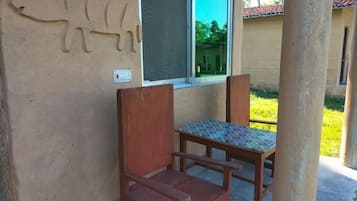 Une chaise et une table en bois se trouvent devant un bâtiment dont la façade est ornée d’une gravure représentant un taureau.
