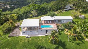 A two-story house with a swimming pool, surrounded by lush greenery and hills. - Villa Olga - Two Bedroom Villa, Sleeps 4 (Le Vauclin)