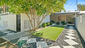 Une maison moderne dotée d’une pelouse bien entretenue, d’un jardin décoratif et d’un chemin menant à l’entrée.