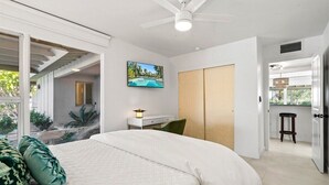 Une chambre moderne avec un grand lit, un bureau, une télévision et une vue sur une piscine.