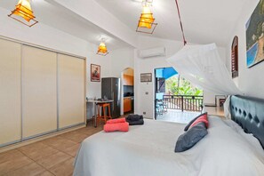 Ein Schlafzimmer mit Bett, Schreibtisch, Stuhl, Balkon und Blick sowie Deckenventilator.