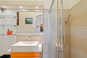 Ein modernes Badezimmer mit Duschkabine aus Glas, einem weißen Waschbecken und einem Holzlagerraum.