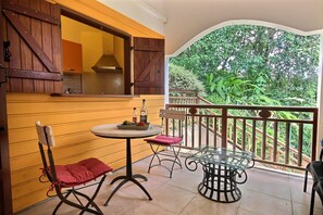 Enjoy a peaceful retreat with a balcony overlooking a serene garden, featuring a round table and two comfortable chairs.