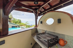 Una cocina con una parrilla, vista al mar y un ventanal redondo.