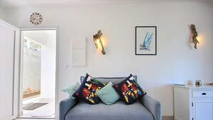 Ein Wohnzimmer mit grauem Sofa, bunten Kissen, einem gerahmten Kunstwerk und rustikaler Wanddekoration.