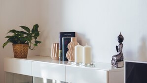 A white console table with a potted plant, books, candles, and a Buddha statue. - Casa Monash (Puerto del Carmen)