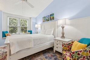 A bedroom with a bed, nightstands, a chair, and artwork on the wall. - Poolside Oasis: Gated Complex, Near Beach and Pool (Fernandina Beach)