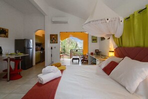 A bedroom with a bed, a desk, a chair, and a view of the outdoors.