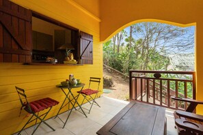 A yellow room with a window, a table with chairs, and a view of trees.
