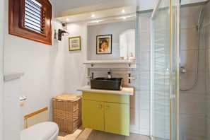 A bathroom with a sink, mirror, and shower.