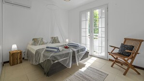 Une chambre avec deux lits, une chaise en bois, une lampe de chevet et une fenêtre avec des volets.