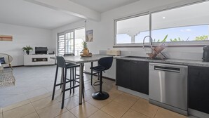 Une cuisine moderne dotée d’une grande fenêtre, d’un lave-vaisselle et d’un coin repas avec des tabourets de bar.