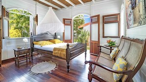 Un dormitorio con cama con dosel, suelo de madera y vistas al exterior con vegetación.