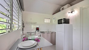 Une cuisine compacte comprenant une table à manger pour deux personnes, un réfrigérateur, un four à micro-ondes et une machine à café.