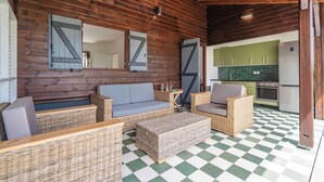 Une cabane en bois chaleureuse, avec un sol à carreaux, des meubles en osier et un coin cuisine.