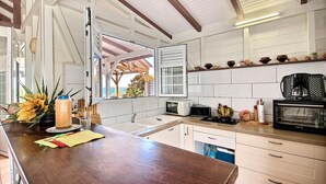 A modern kitchen with white cabinets, a wooden countertop, and a built-in microwave. - Villa K'lia - Two Bedroom Cottage, Sleeps 4 (Le Robert)
