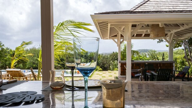 Una mesa con vista a una piscina, palmeras, un quiosco y asientos al aire libre.