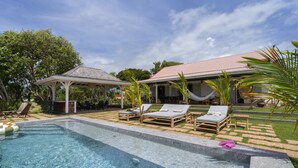 Un área de piscina con sillones de descanso y un pabellón.