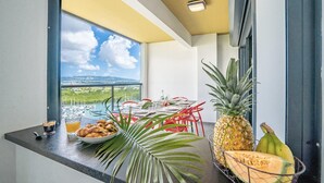 Ein Balkon mit Esstisch für zwei Personen, dekoriert mit tropischen Früchten und Blick auf eine Marina.