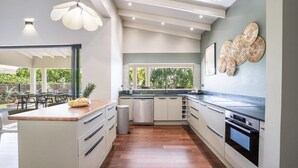 A modern kitchen with a central island, built-in appliances, and a large window overlooking a garden. - Villa Cactus - Three Bedroom Villa, Sleeps 6 (Le François)