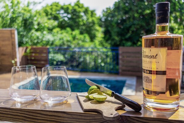 A bottle of Pliment on a wooden table with two empty glasses and a knife with lime wedges.