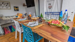 A dining area with a wooden table set for two, featuring a fruit basket, glasses, and a bottle. - Villa Ti Pagerie - Two Bedroom Villa, Sleeps 4 (Les Trois-Îlets)