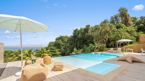 A pool area with lounge chairs, a table, and an umbrella. - Villa Alexina - Four Bedroom Villa, Sleeps 8 (Le Robert)