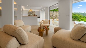 A modern living room with beige sofas, a wicker chair, and a small wooden table with a fruit bowl. - Villa Alexina - Four Bedroom Villa, Sleeps 8 (Le Robert)