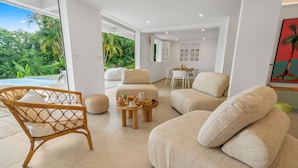 A modern living room with a pool view, a dining area, and a kitchen. - Villa Alexina - Four Bedroom Villa, Sleeps 8 (Le Robert)