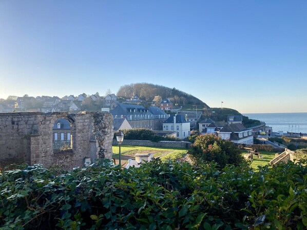 A coastal town with historic buildings, a prominent hill, and a clear view of the sea. - Les pénates, near beach, picturesque village (Veules-les-Roses)
