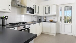 A modern kitchen with white cabinets, a gas stove, a microwave, and a coffee maker. - Villa Gabriella con Piscina by Wonderful Italy (Ostuni)