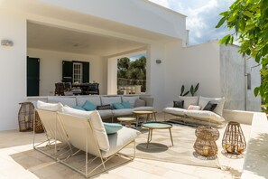 Een terras met een zithoek, een eettafel en twee bijzettafeltjes.