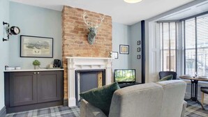 A living room with a fireplace, a sofa, a television, and a window with blinds. - 15a Furness House (Hartlepool)