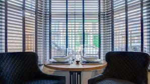 A room with a round table, two chairs, and a view through a window with blinds. - 15a Furness House (Hartlepool)