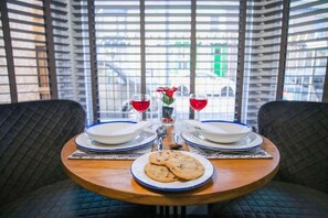 A dining table with plates, glasses, and cookies, set in a room with large windows and a view of buildings.