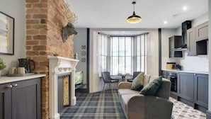 A modern kitchen with dark cabinets, a fireplace, and a plaid-patterned floor. - 15a Furness House (Hartlepool)