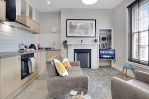 A modern kitchen with a built-in oven, a dining area with a sofa, a fireplace, and a television.